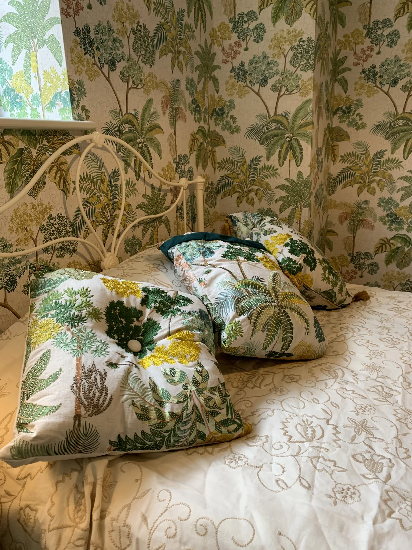 A close-look at layering at work — patterned cushion, fringed throw, painted spindle chair against soft striped drapes