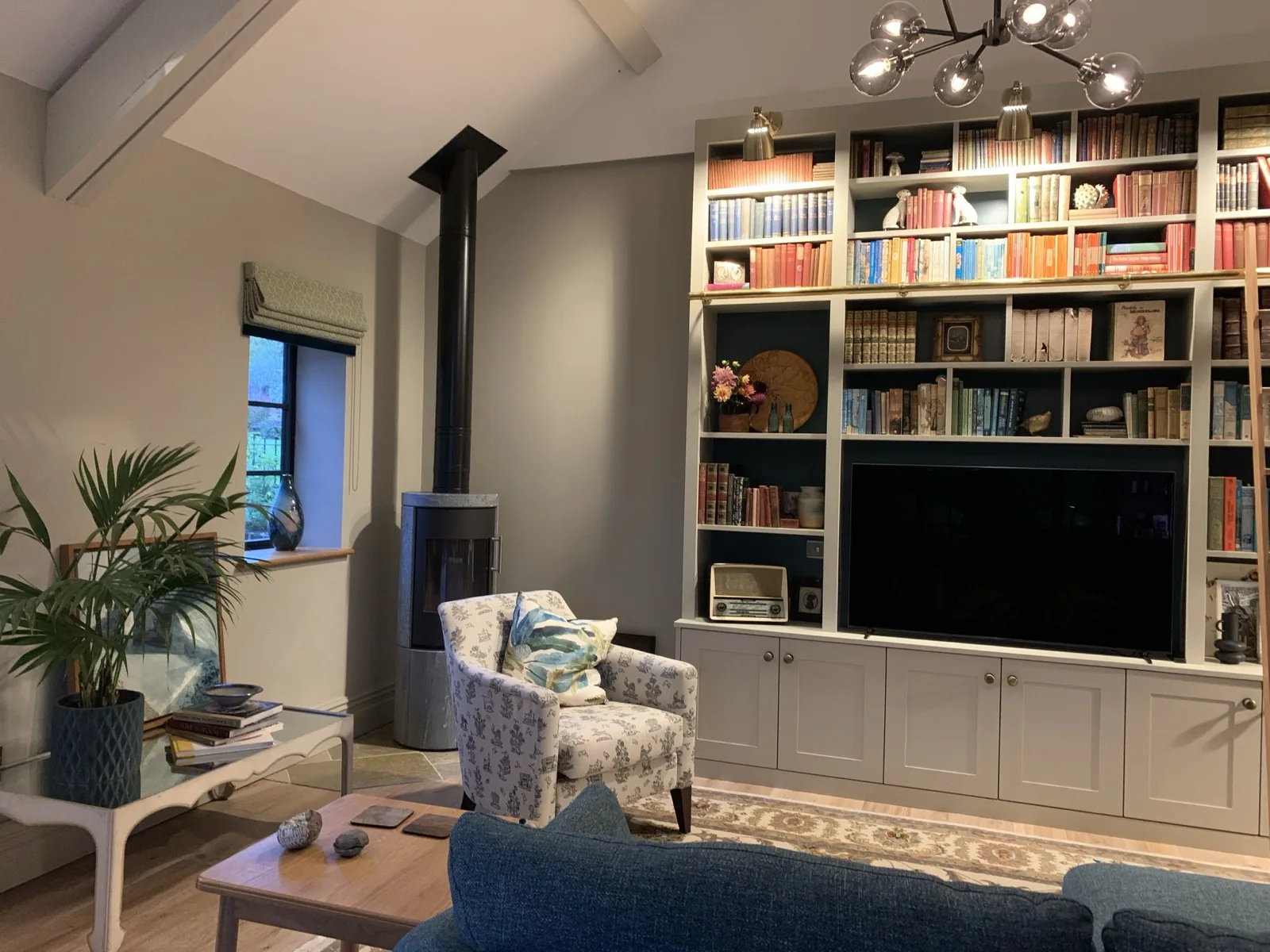 The Apple Loft — open-plan living room with bespoke bookshelf wall, log burner, and botanical styling