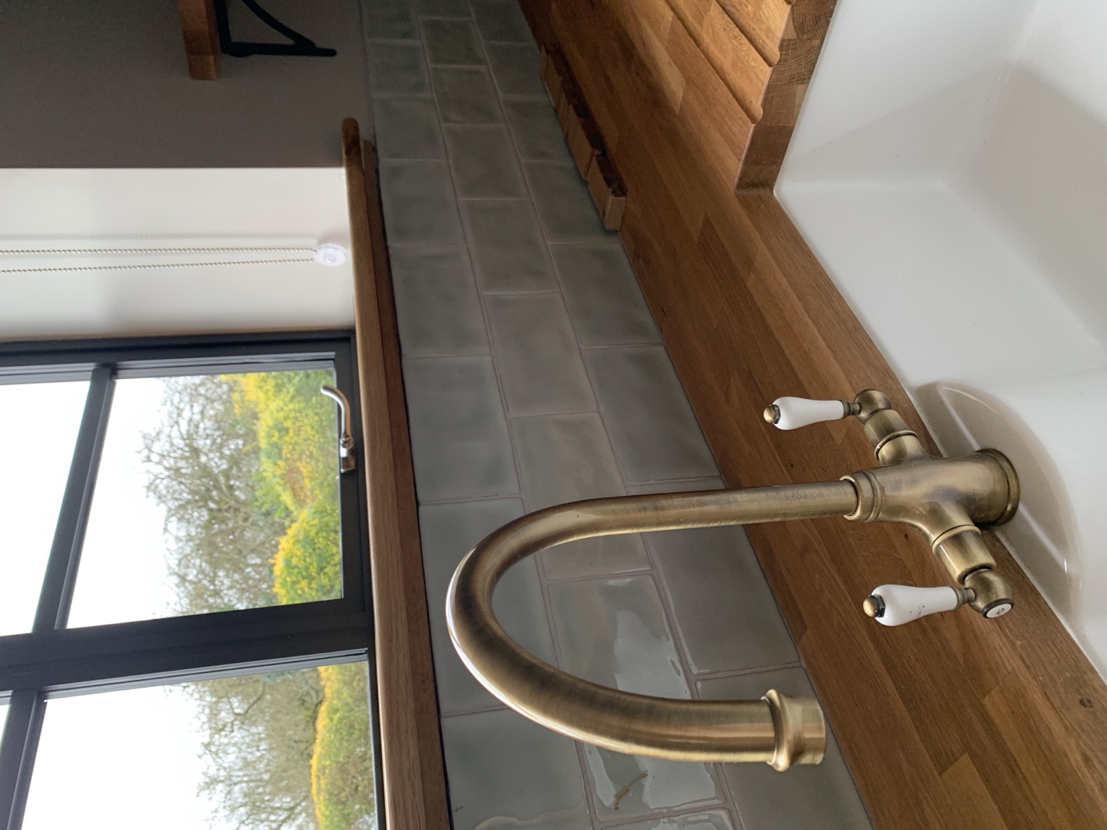 Brass tap detail with oak worktop and countryside view