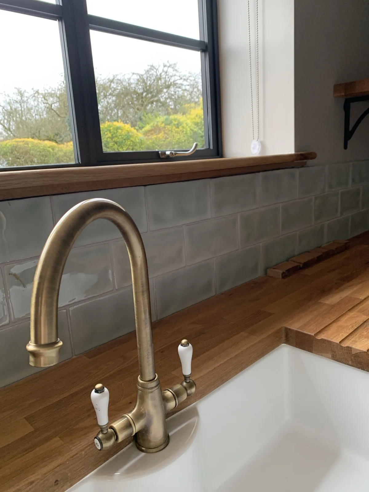 Brass tap detail with oak worktop and countryside view