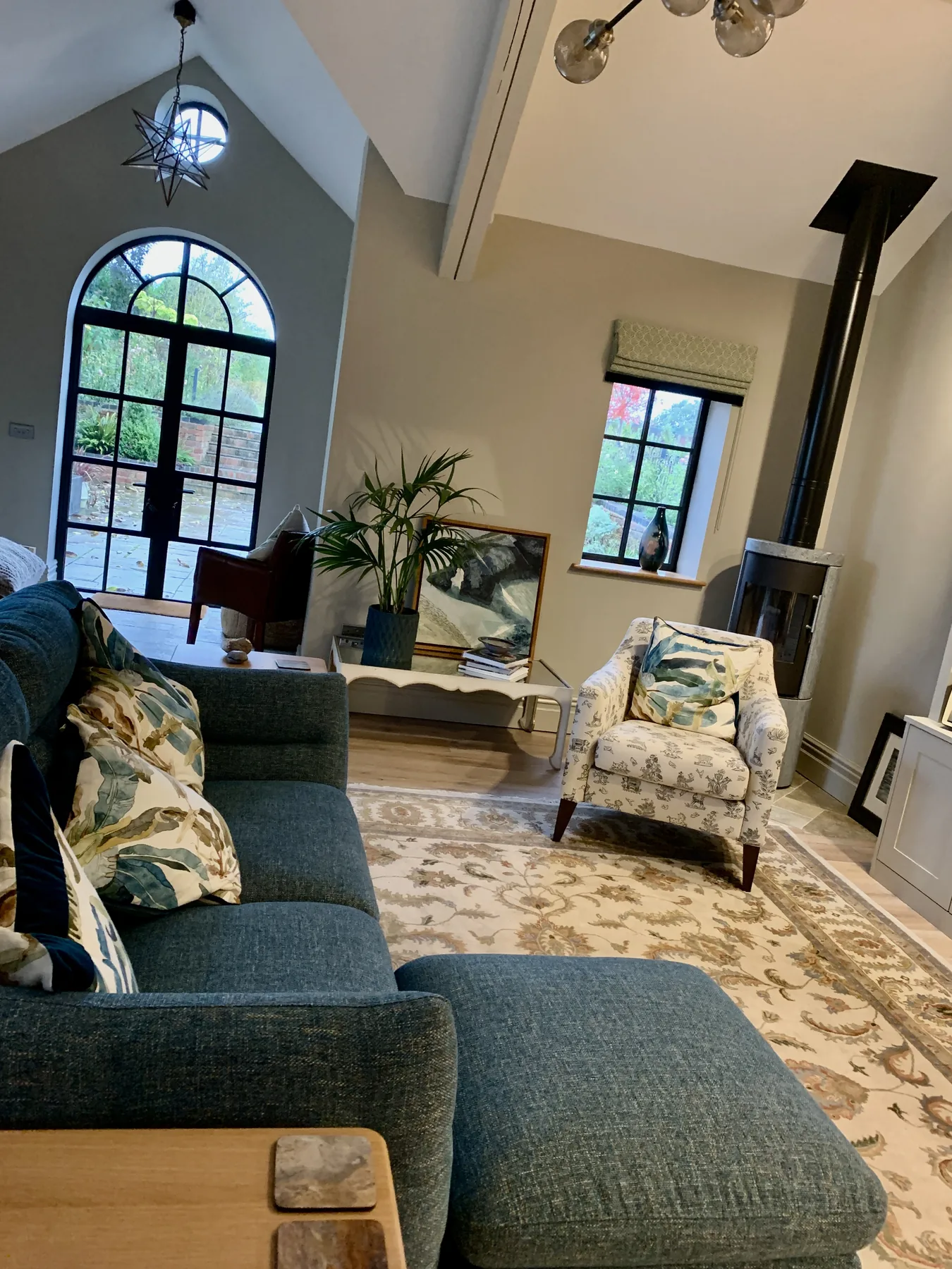 The Apple Loft — vaulted living space with bespoke library wall, brass-rail ladder, and a quiet log burner beyond