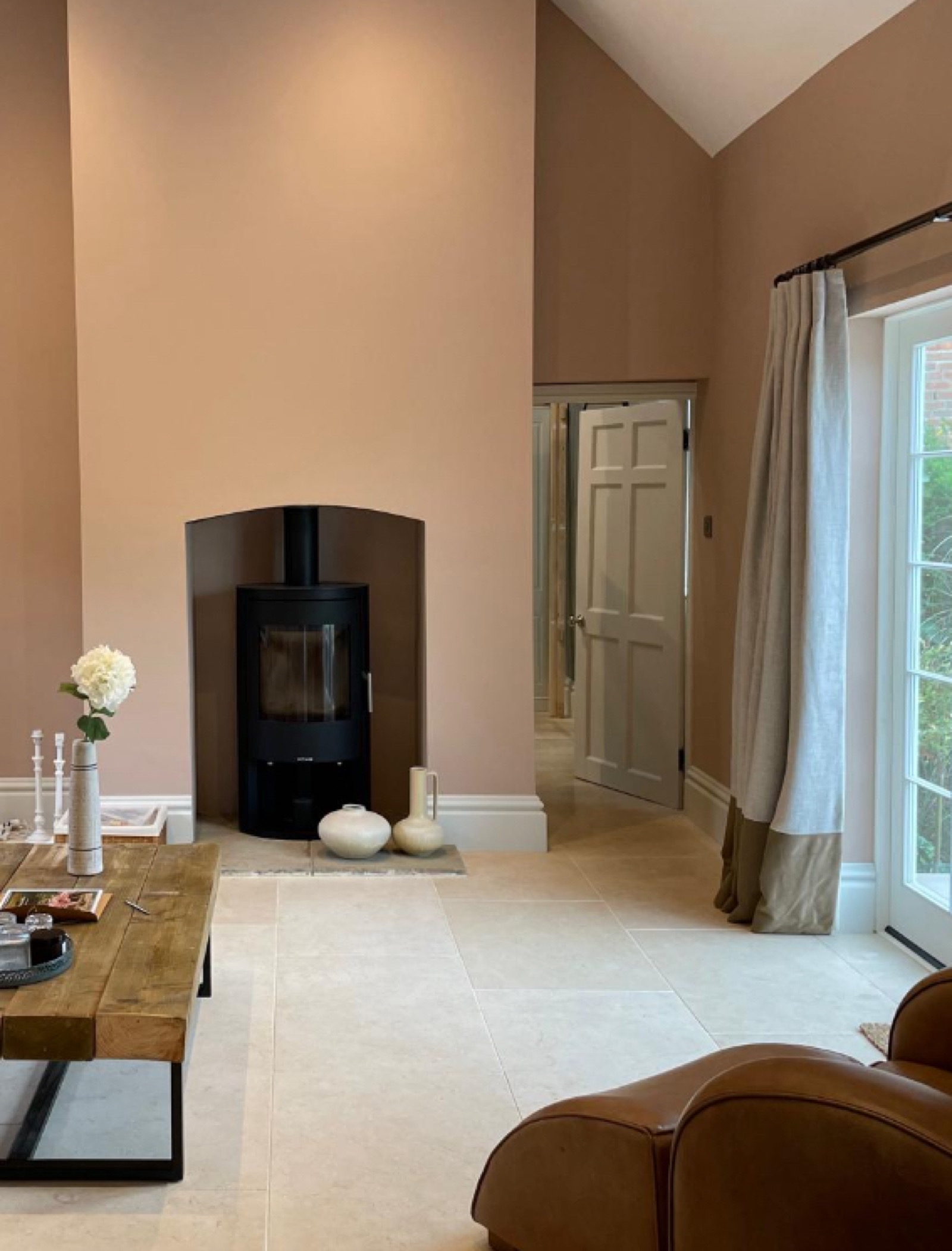 Elegant living room with log burner, vaulted ceiling, and linen curtains
