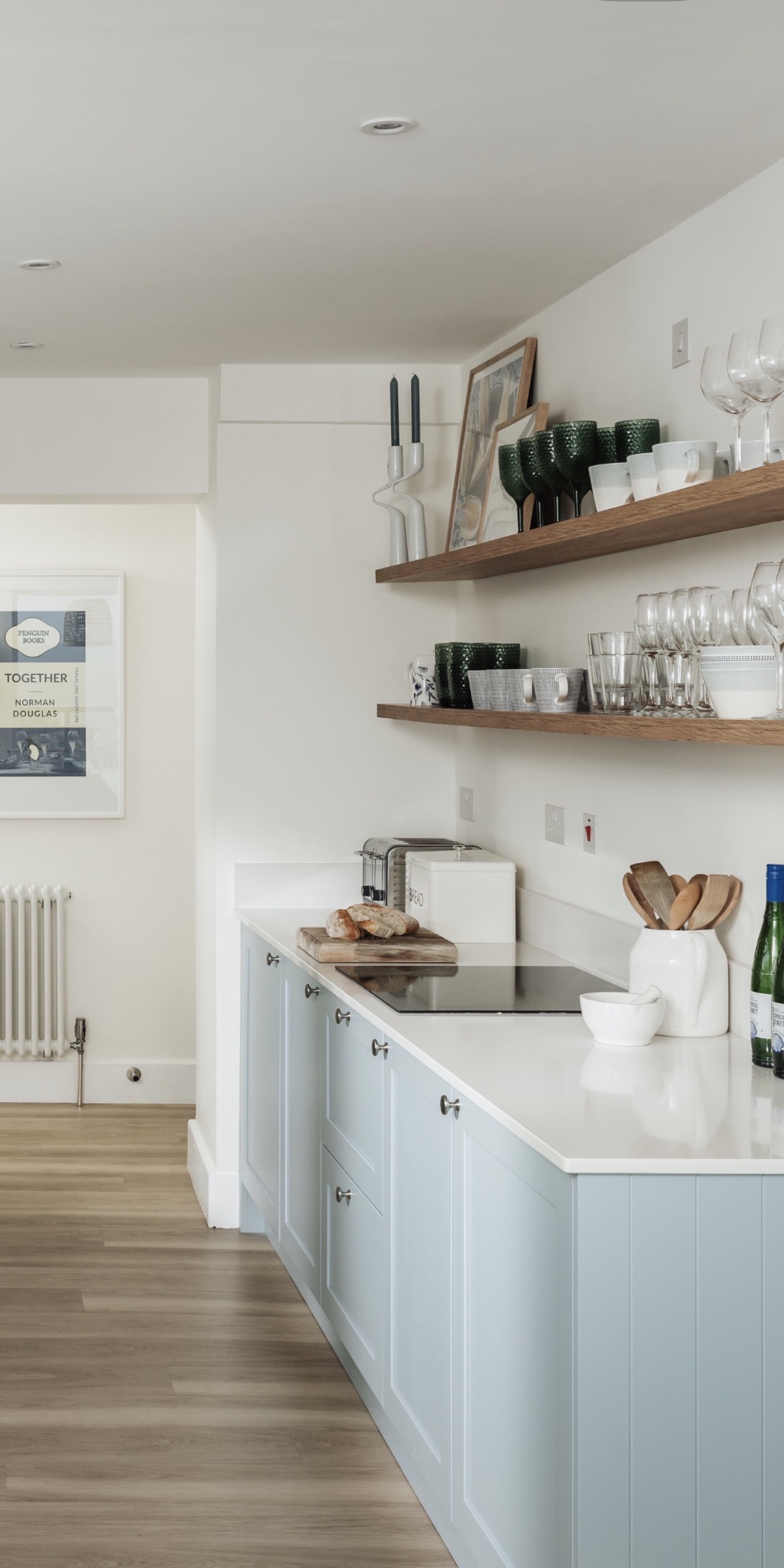 Coastal holiday let kitchenette with pale blue shaker cabinets and open shelving