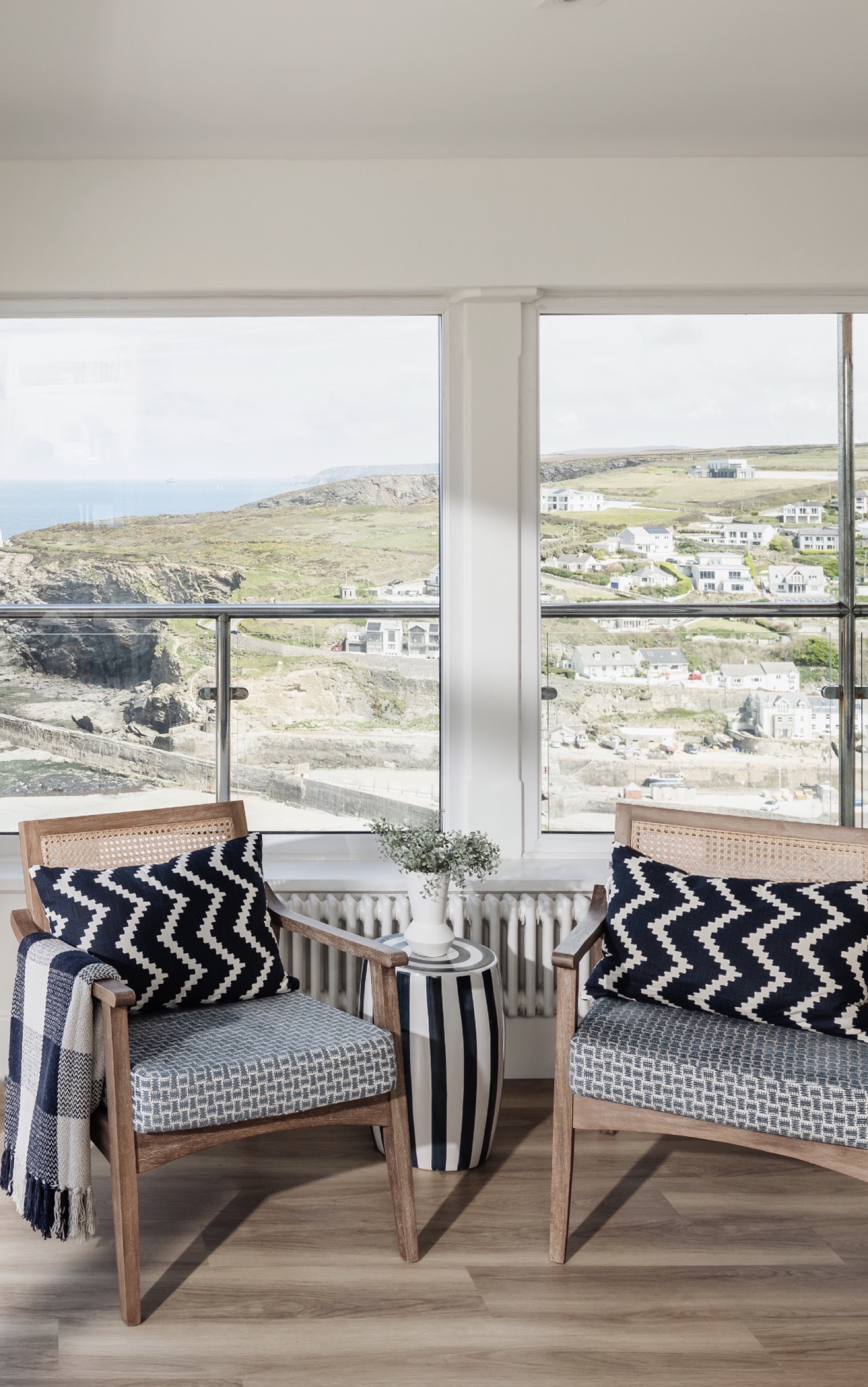 Coastal holiday let seating nook with accent chairs and panoramic sea view