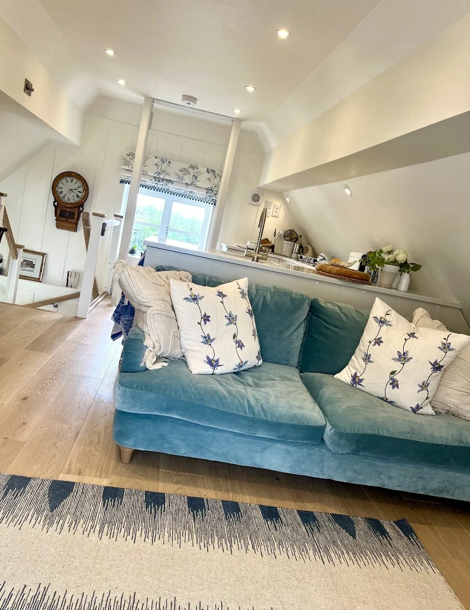 Future-proof living — a bright, adaptable loft sitting and kitchen space with teal sofa, vaulted ceiling, and seamless transition between zones